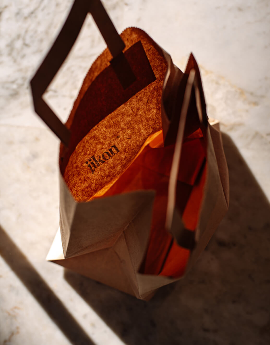 Jikon branded paper shopping bag with handles on a surface